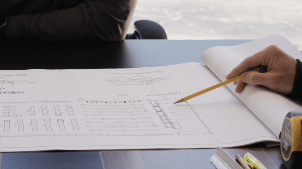 Person reviewing architectural blueprint with pencil