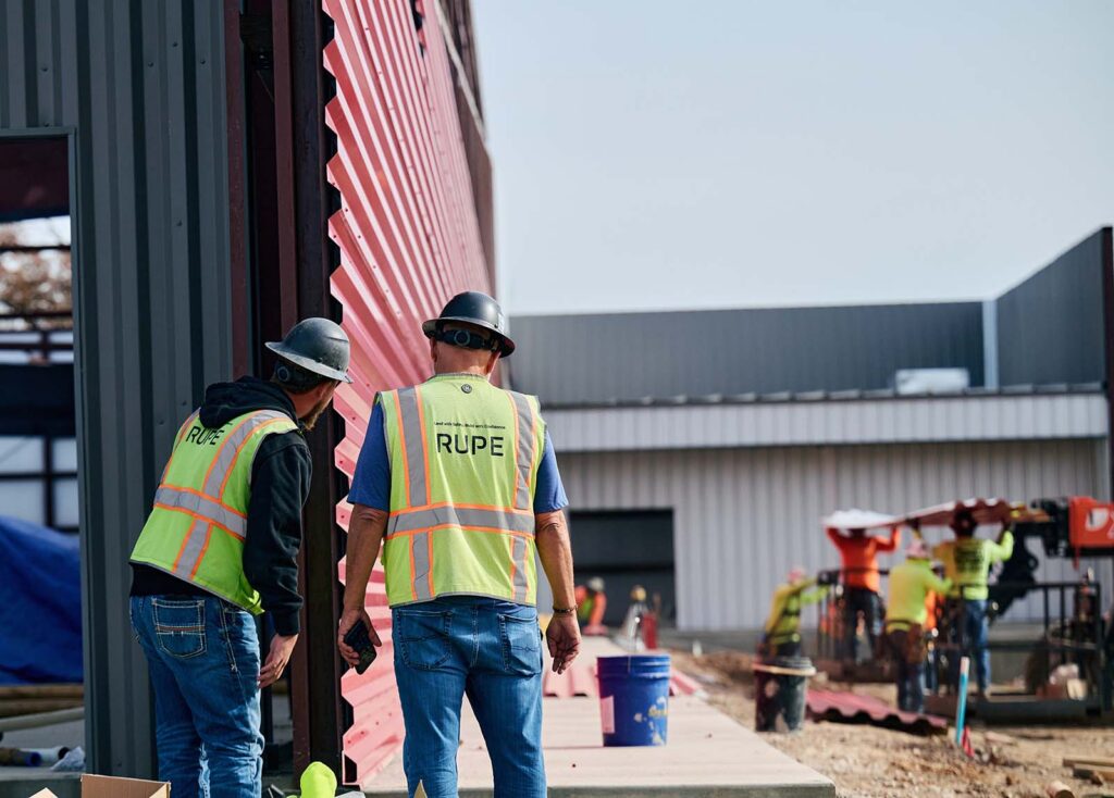 Construction workers inspect metal siding at industrial building